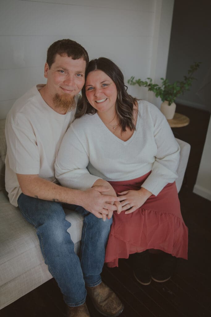 couple looking into camera sitting on couch smiling