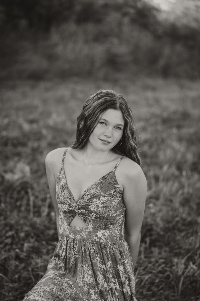 black and white senior photo girl sitting in a field