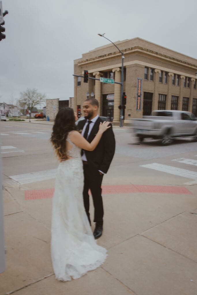 bride and groom standing on street with cars driving by