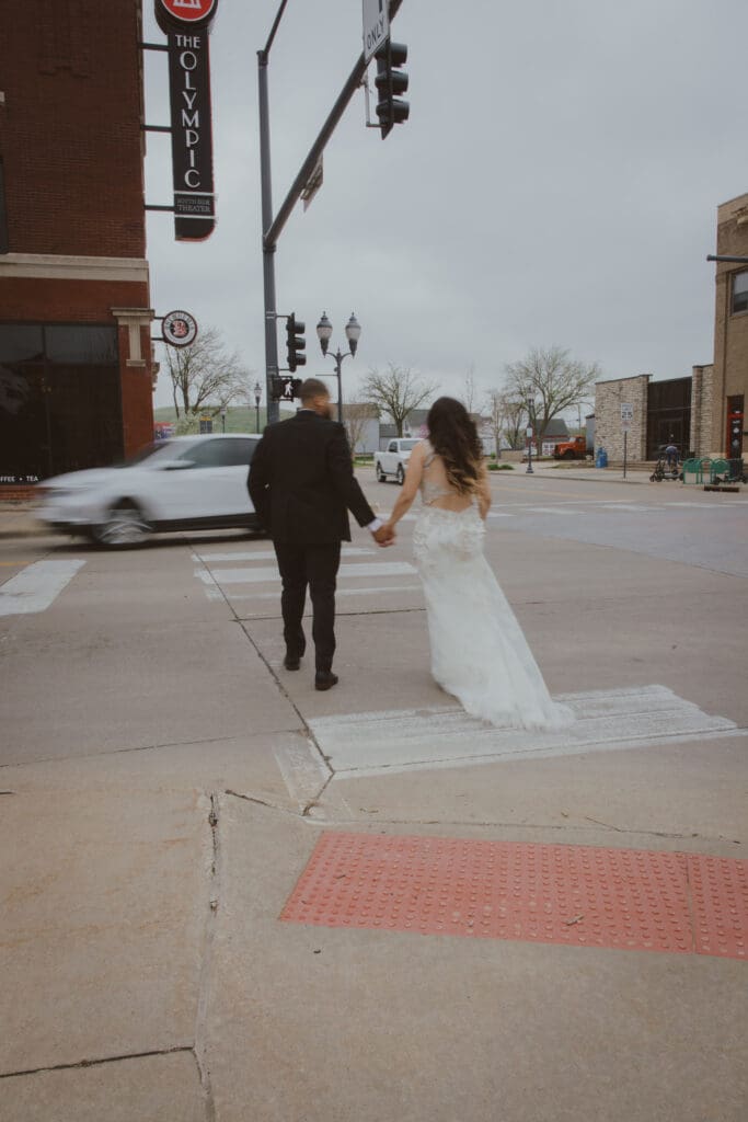 bride and groom holding hands walking on crosswalk