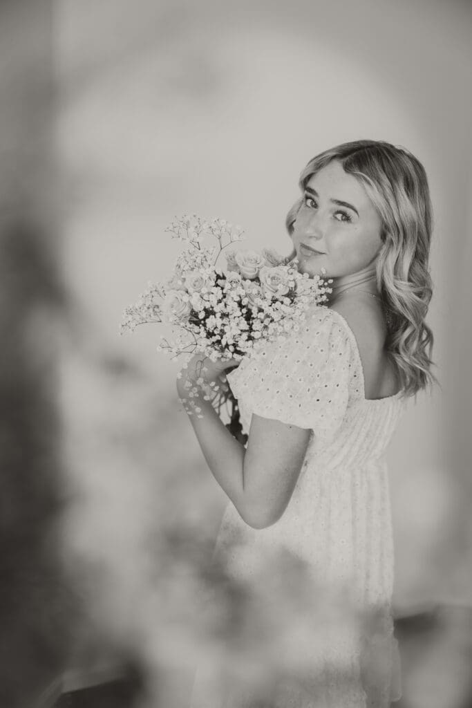 black and white senior girl image white dress holding flowers