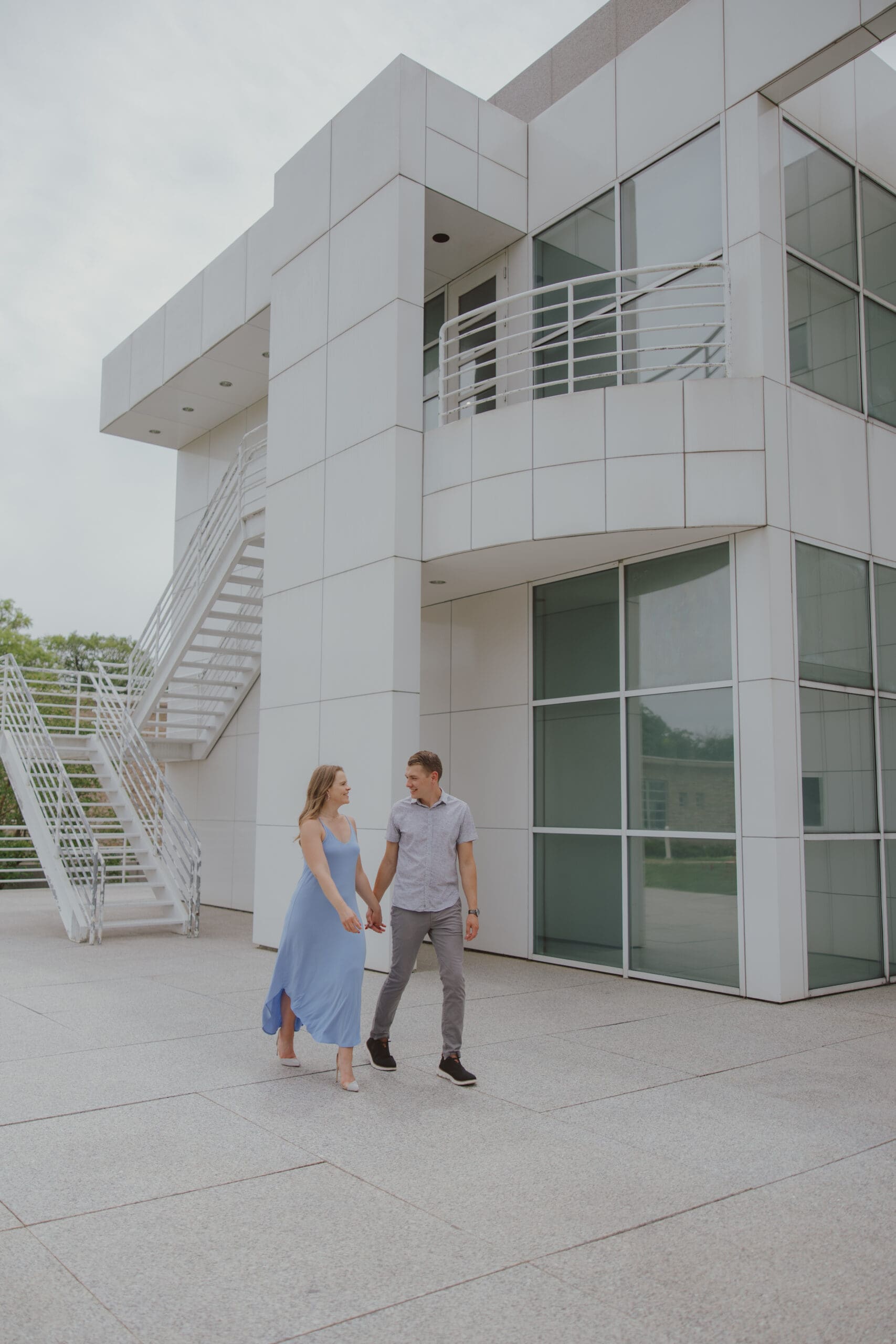 couple walking near tall white building and stairs