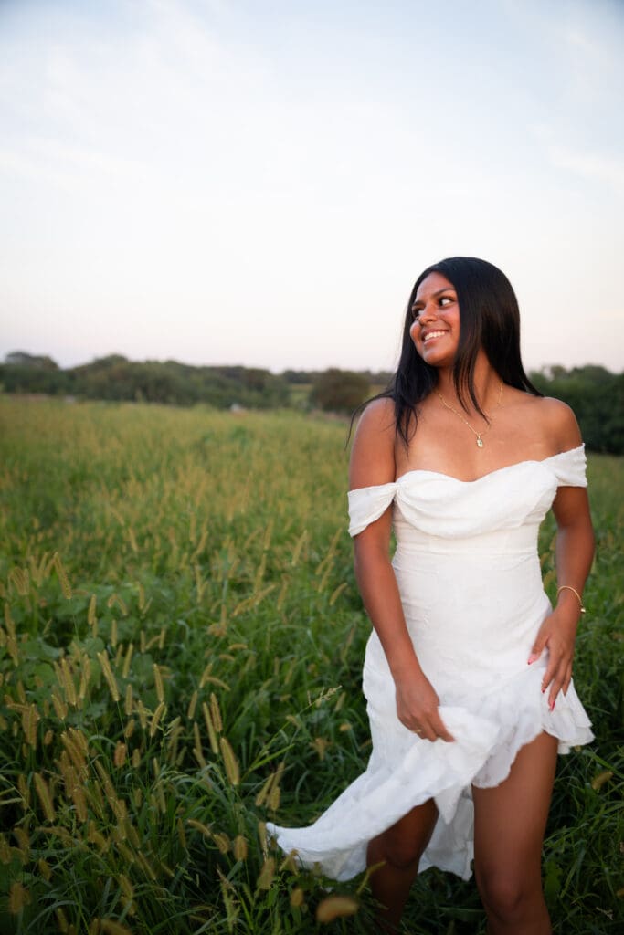 senior girl in white dress running in field