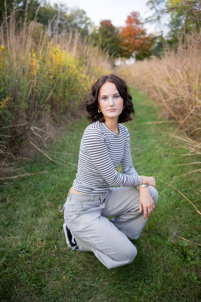 senior girl in tall grass on pathway in fall