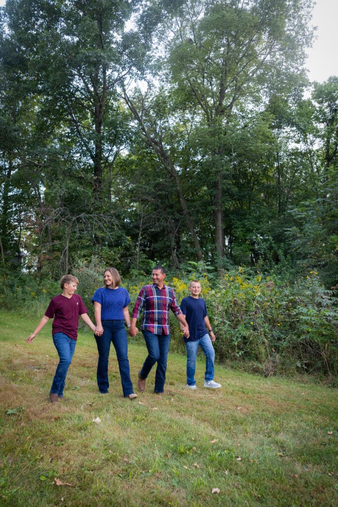 Family walking together in a wooded area during fall family session in Washington, Iowa.