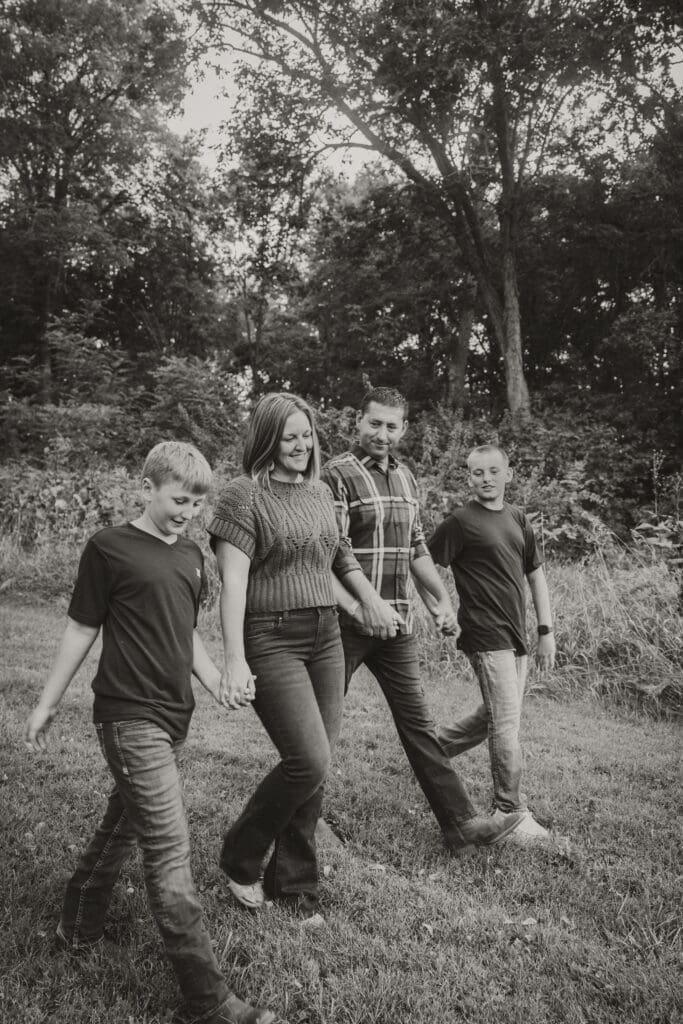 black and white family walking photo near trees and tall grass