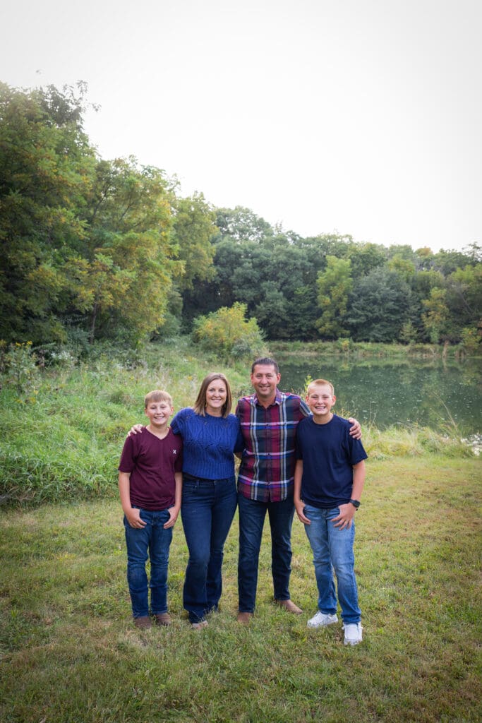 Family standing together in a wooded area during fall family session in Washington, Iowa.