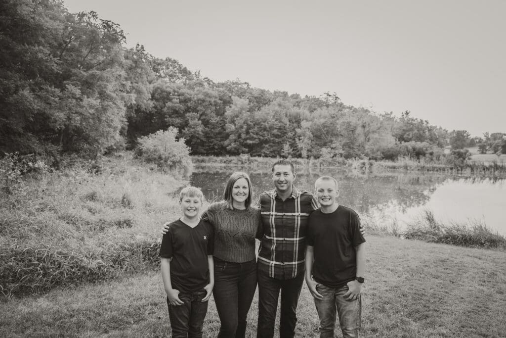 Family standing together in a wooded area during fall family session in Washington, Iowa.