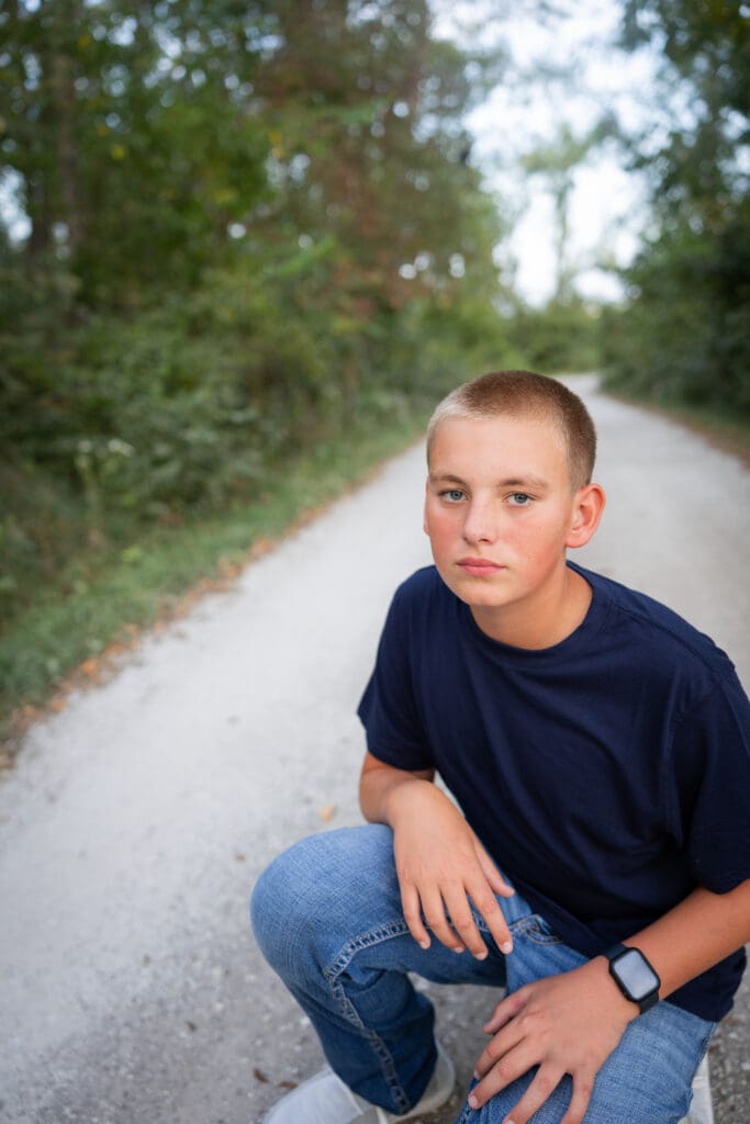 Older son sitting during outdoor Iowa family session.