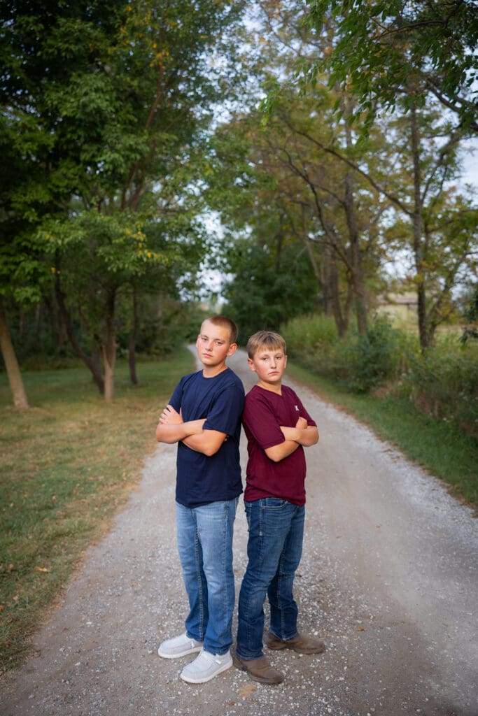 Brothers standing back-to-back on gravel lane during family session.