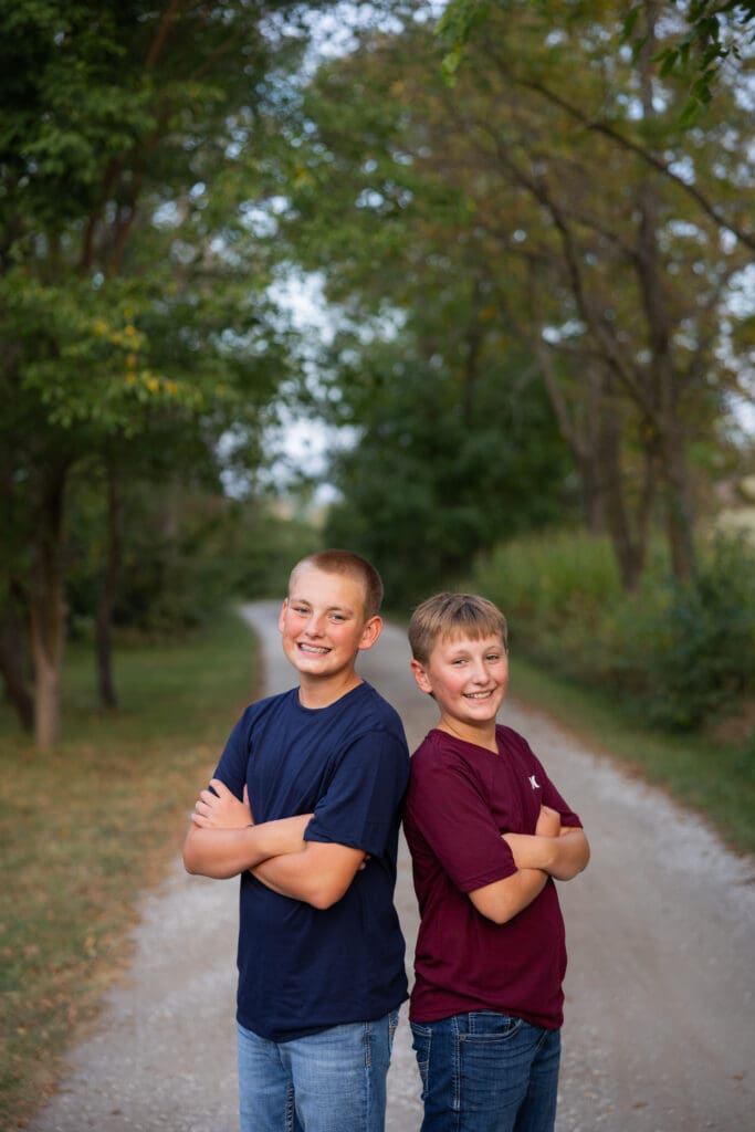 Brothers standing back-to-back on gravel lane during family session.