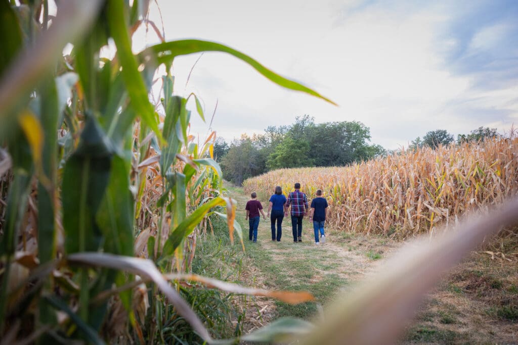 Family walking together in a field during fall family session in Washington, Iowa.