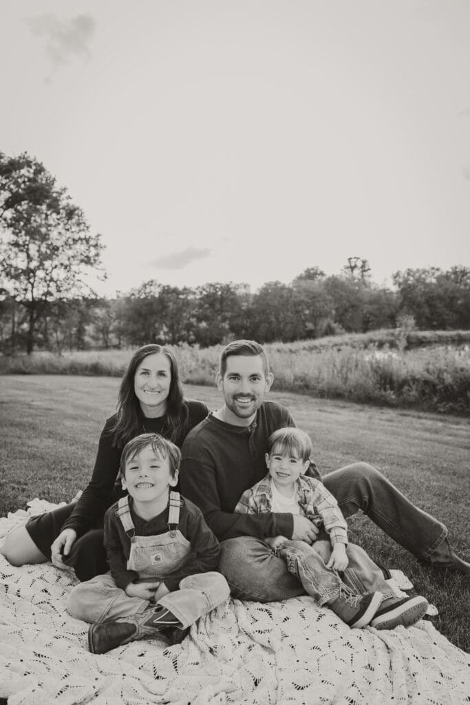 Black and white photo of the family sitting on a blanket in an open field.