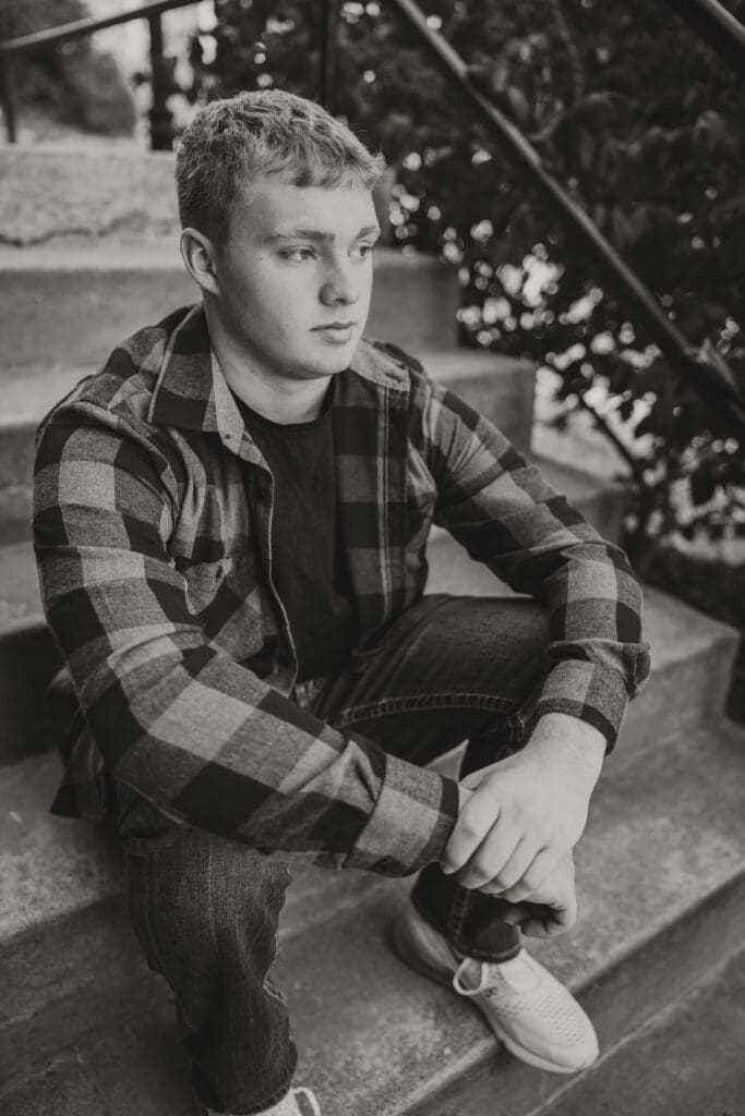 Black and white outdoor photo of senior guy on steps