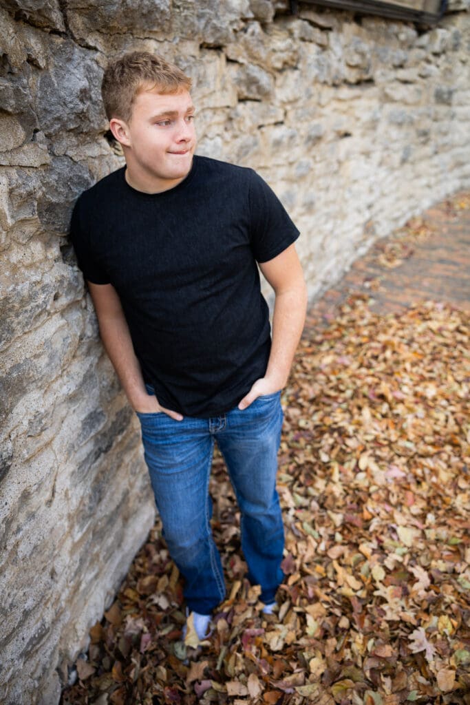 Senior Guy leaning on wall in fall outdoor photos