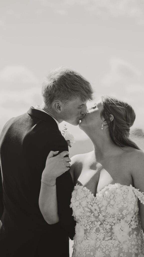 Black and white photo of bride and groom kissing